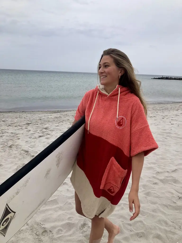 Femeie cu o placa de surf care poarta un poncho plaja dama din bumbac, culoare rosu deschis, rosu inchis, crem