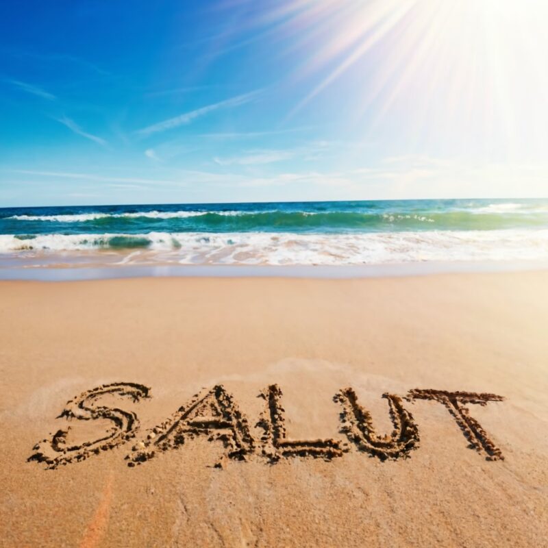 cuvantul „Salut” scris pe o plaja, in nisip